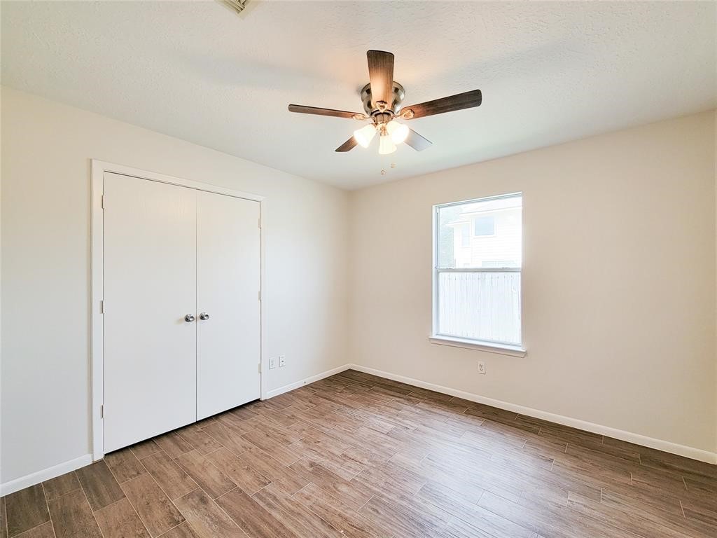 19331 River Bottom Road Katy, TX 77449 - Photo 11 of 23 an empty room with wooden floor fan and windows
