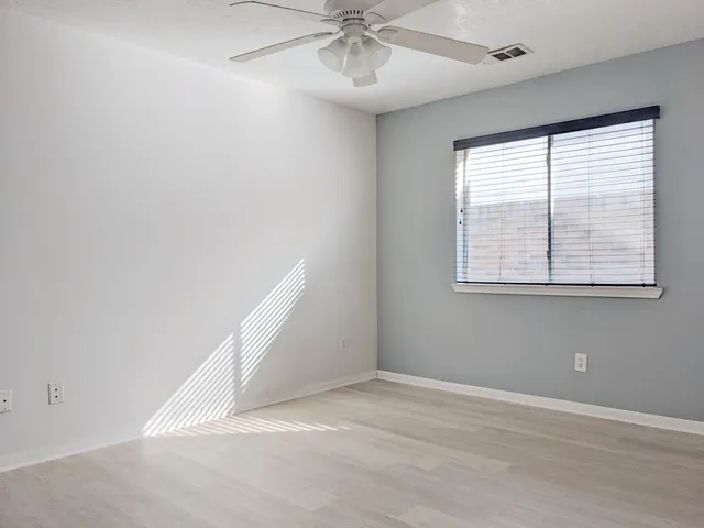an empty room with a window and a ceiling fan