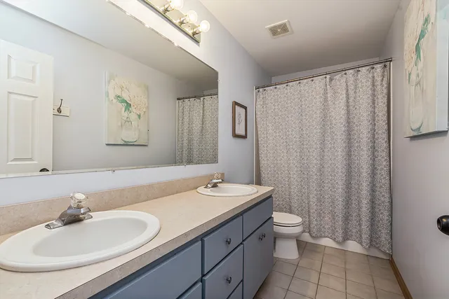 a bathroom with a double vanity sink toilet and a mirror