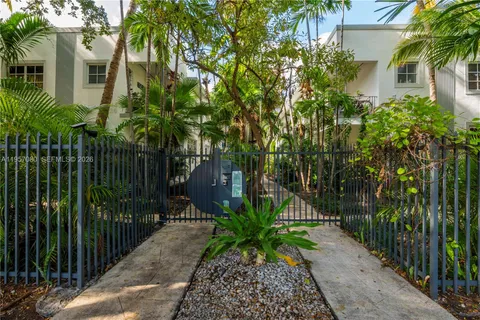 a view of a pathway of a house with a small yard and wooden fence