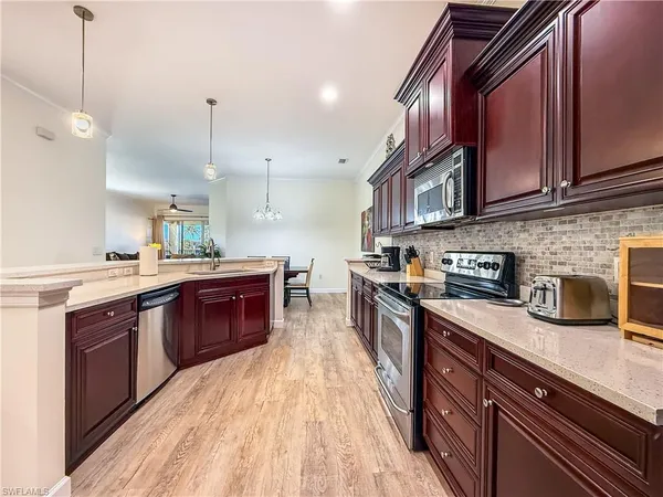 a large kitchen with stainless steel appliances granite countertop a stove a sink dishwasher and a refrigerator with wooden floor