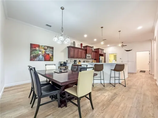 a dining room with wooden floor a chandelier a wooden table and chairs