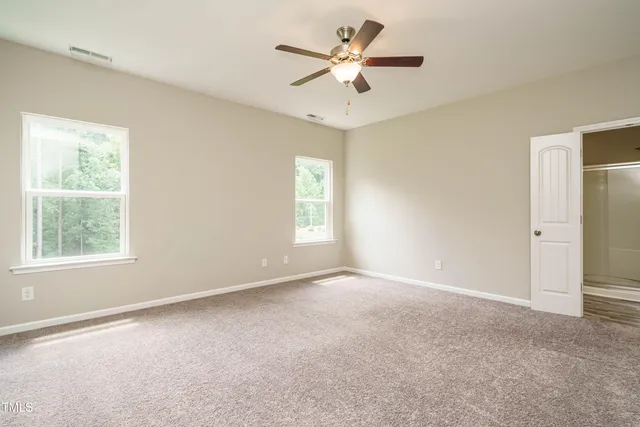 an empty room with a window and a fan