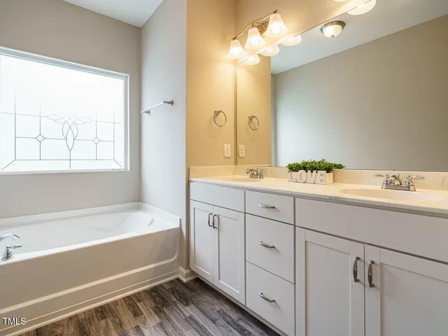 a spacious bathroom with a tub sink and mirror