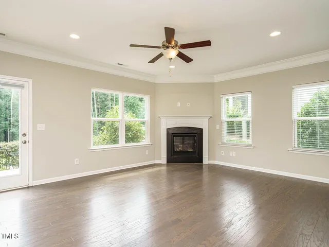 an empty room with wooden floor fan and windows