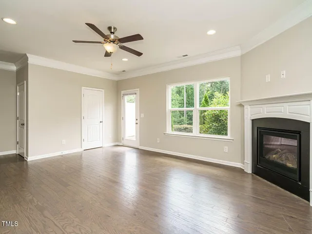 an empty room with wooden floor a ceiling fan and a fireplace