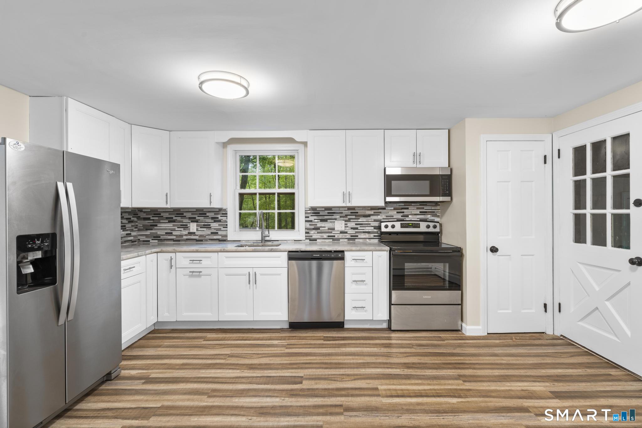 7 Sycamore Terrace Windham, CT 06280 - Photo 9 of 40 a kitchen with granite countertop a refrigerator stove and white cabinets