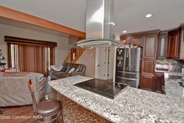 a kitchen with stainless steel appliances kitchen island granite countertop a refrigerator a stove and a sink