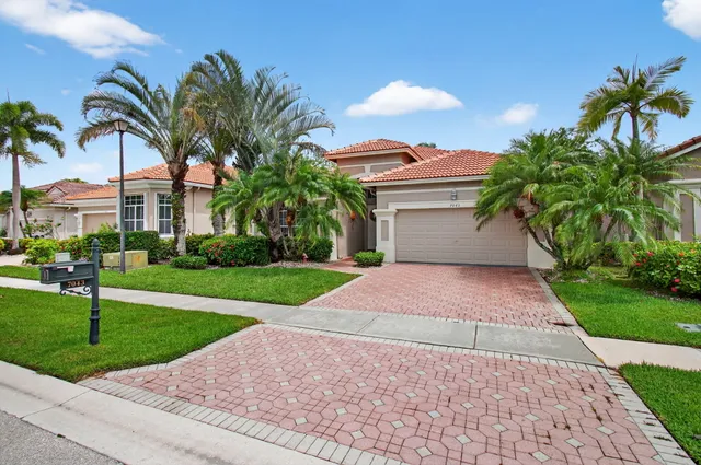 a front view of a house with a yard and palm trees