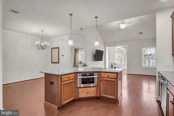 a large kitchen with kitchen island a stove a sink a refrigerator and white cabinets with wooden floor