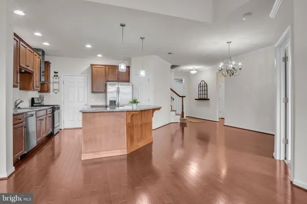 a view of kitchen with stainless steel appliances granite countertop a stove top oven and a refrigerator with wooden floor