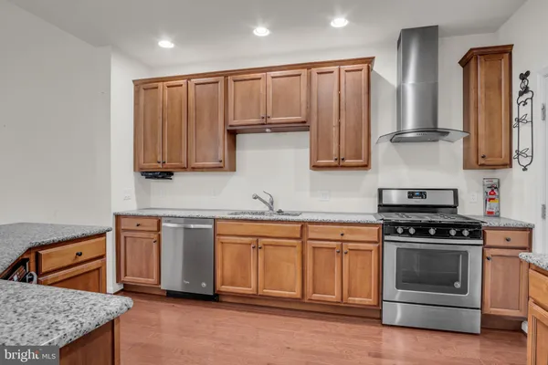 a kitchen with stainless steel appliances granite countertop a refrigerator a stove and a sink with wooden floor