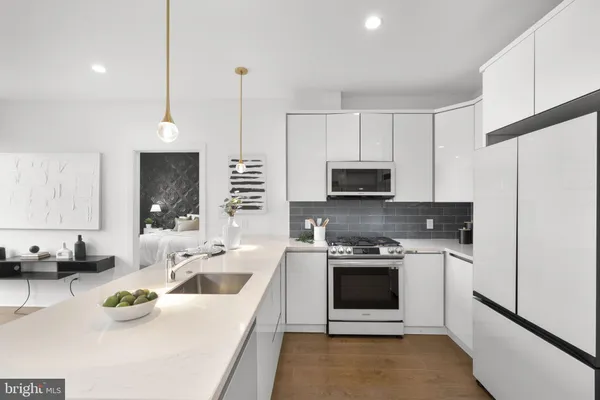 a kitchen with stainless steel appliances a stove a sink a microwave a refrigerator and white cabinets