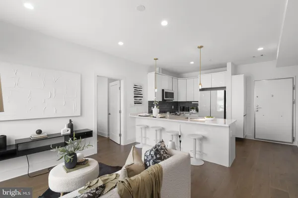 a large white kitchen with stainless steel appliances kitchen island granite countertop a couch and a stove