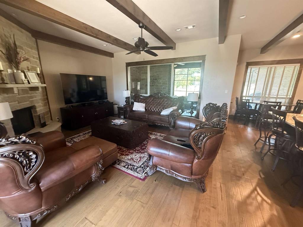 125 Lucky Ridge Lane Boyd, TX 76023 - Photo 17 of 29 Living area with wood-type flooring, a ceiling fan, beam ceiling, and a fireplace