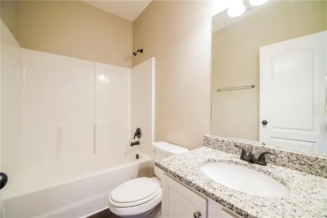 a bathroom with a granite countertop sink a toilet and shower