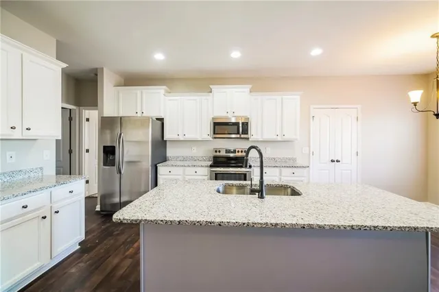 a kitchen with granite countertop a refrigerator and a stove top oven