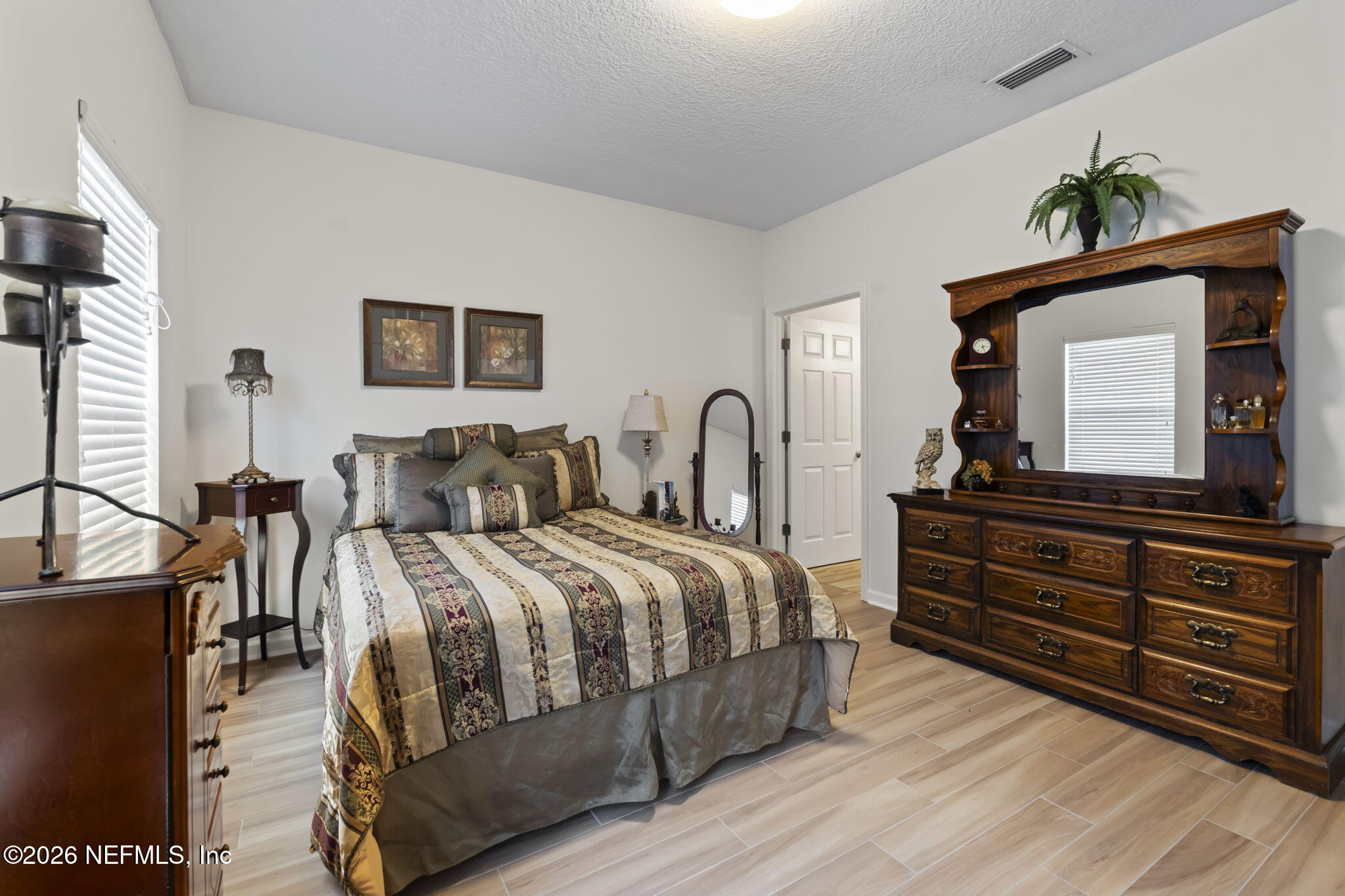 8218 Green Parrot Road, Unit 105 Jacksonville, FL 32256 - Photo 20 of 42 a bedroom with a bed and a dresser with wooden floor