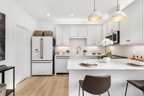 a kitchen with stainless steel appliances granite countertop a refrigerator a sink dishwasher a stove a dining table and chairs with wooden floor