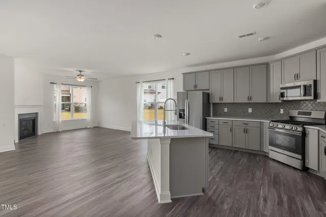 a view of a big room with wooden floor kitchen view and a window