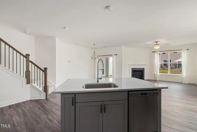 a kitchen with stainless steel appliances granite countertop a stove top oven a sink dishwasher and a refrigerator with wooden floor