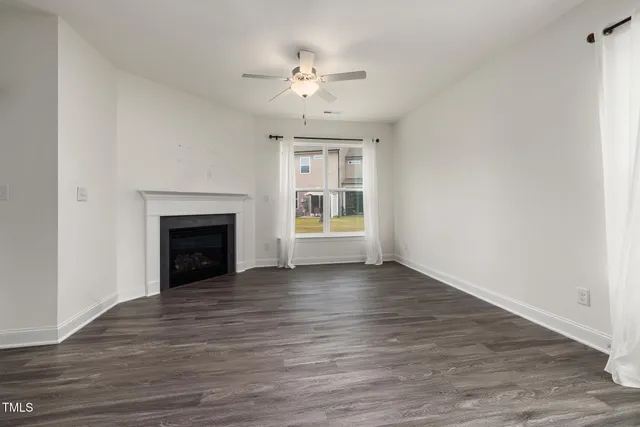 a view of an empty room with a fireplace and a window