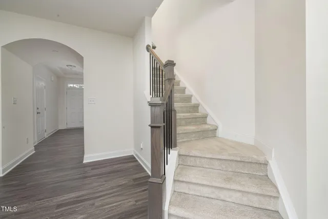 a view of an empty room with wooden floor fireplace and a window