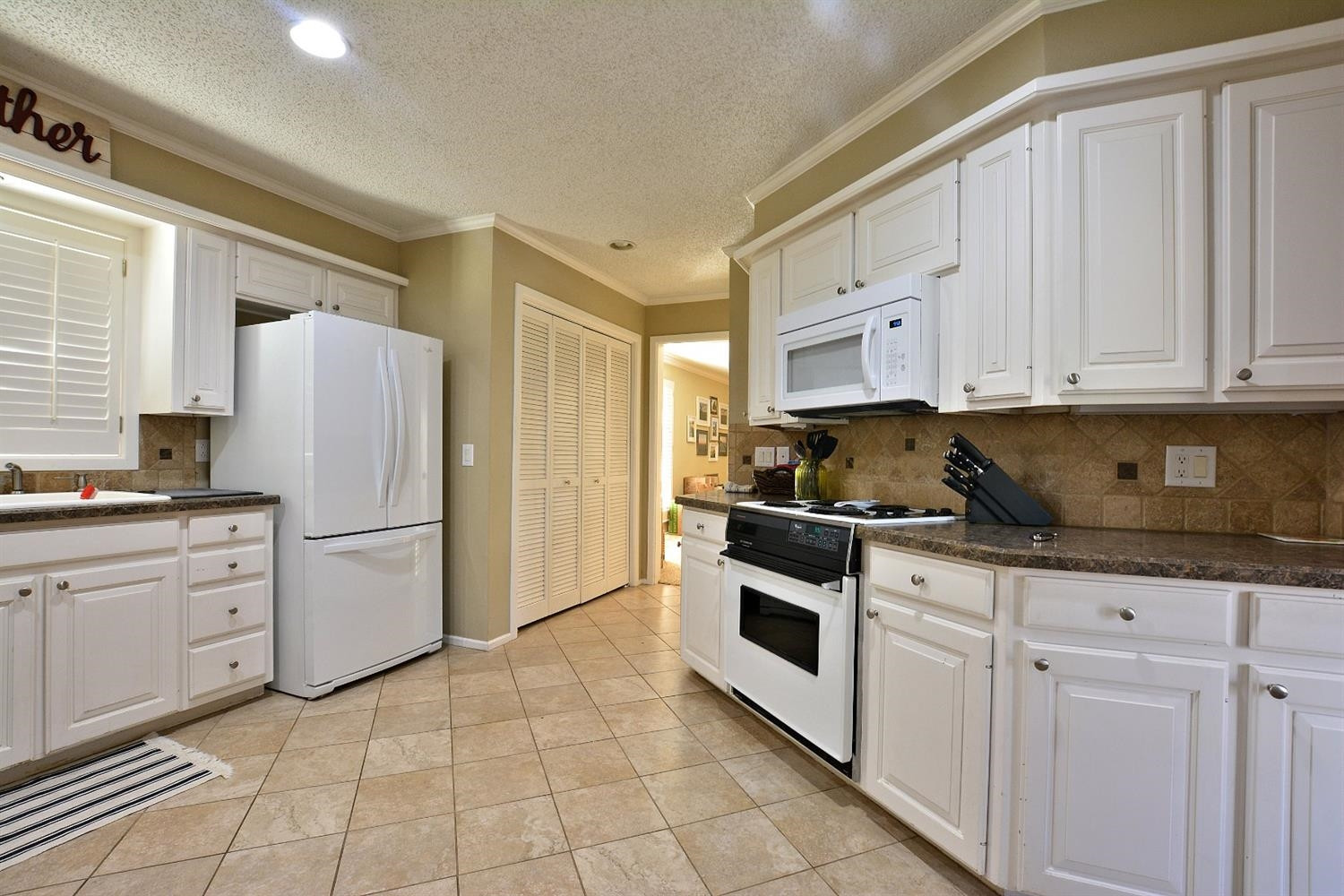 3307 74th Street, Unit A Lubbock, TX 79423 - Photo 2 of 19 a kitchen with granite countertop a white stove a refrigerator and white cabinets