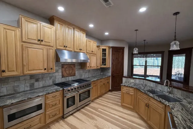 a kitchen with stainless steel appliances granite countertop a stove a sink and a granite counter tops with white cabinets