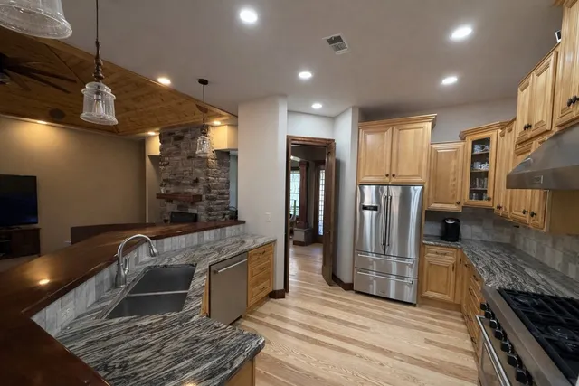 a kitchen with stainless steel appliances granite countertop a refrigerator and a stove