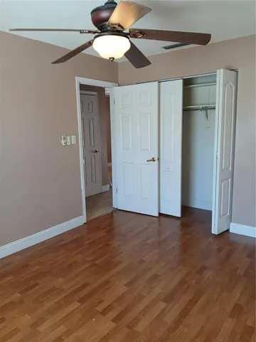 an empty room with wooden floor a ceiling fan and closet