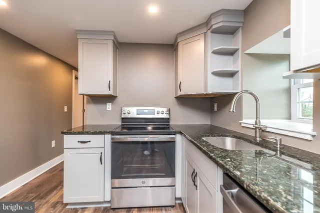 a kitchen with granite countertop a sink stove and cabinets