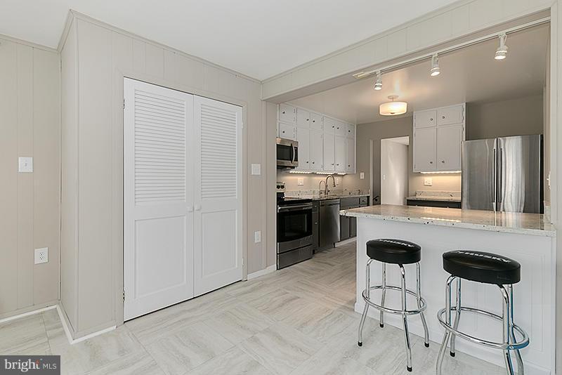 12912 Holdridge Road Silver Spring, MD 20906 - Photo 6 of 25 a kitchen with stainless steel appliances kitchen island granite countertop a refrigerator and cabinets