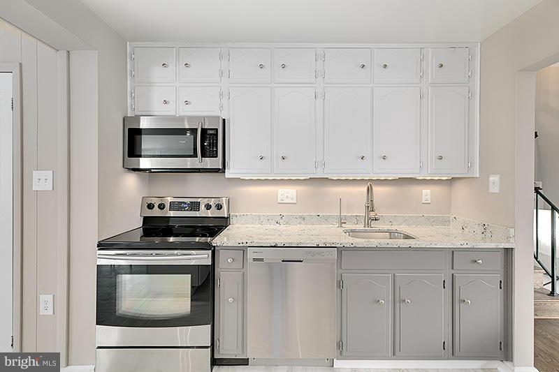 12912 Holdridge Road Silver Spring, MD 20906 - Photo 7 of 25 a kitchen with granite countertop white cabinets and stainless steel appliances
