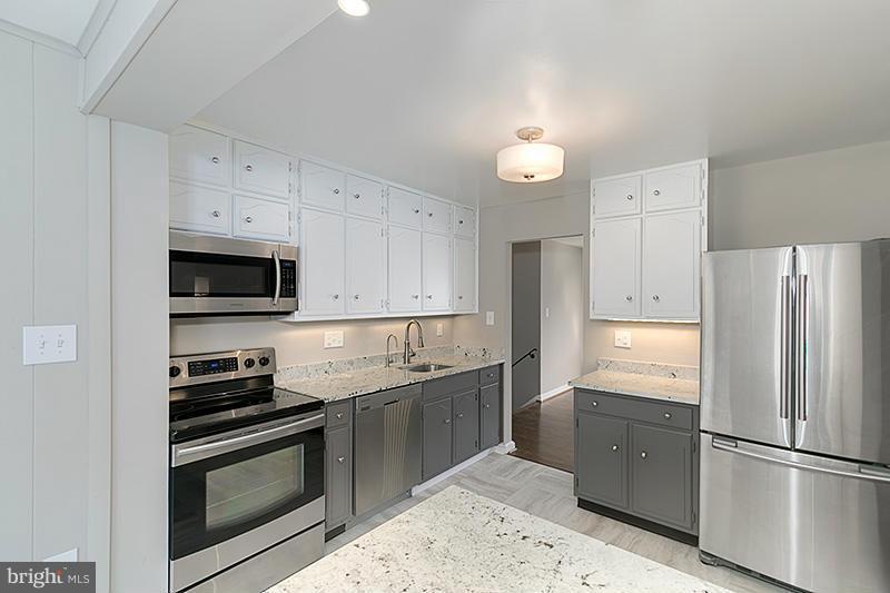 12912 Holdridge Road Silver Spring, MD 20906 - Photo 9 of 25 a kitchen with stainless steel appliances granite countertop a refrigerator sink and stove