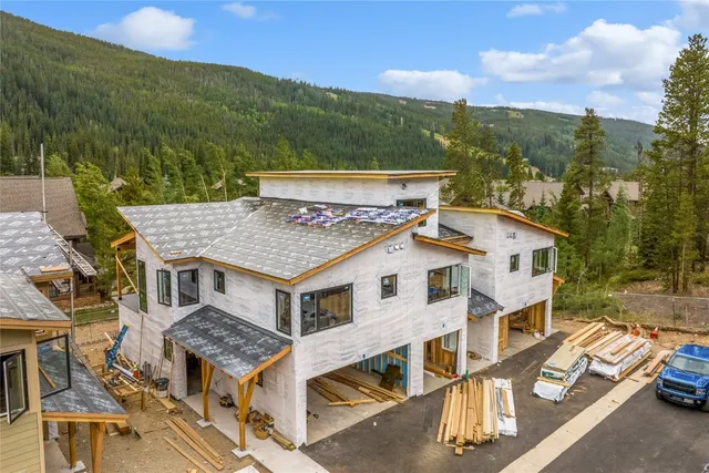 an aerial view of residential houses with yard and mountain view in back