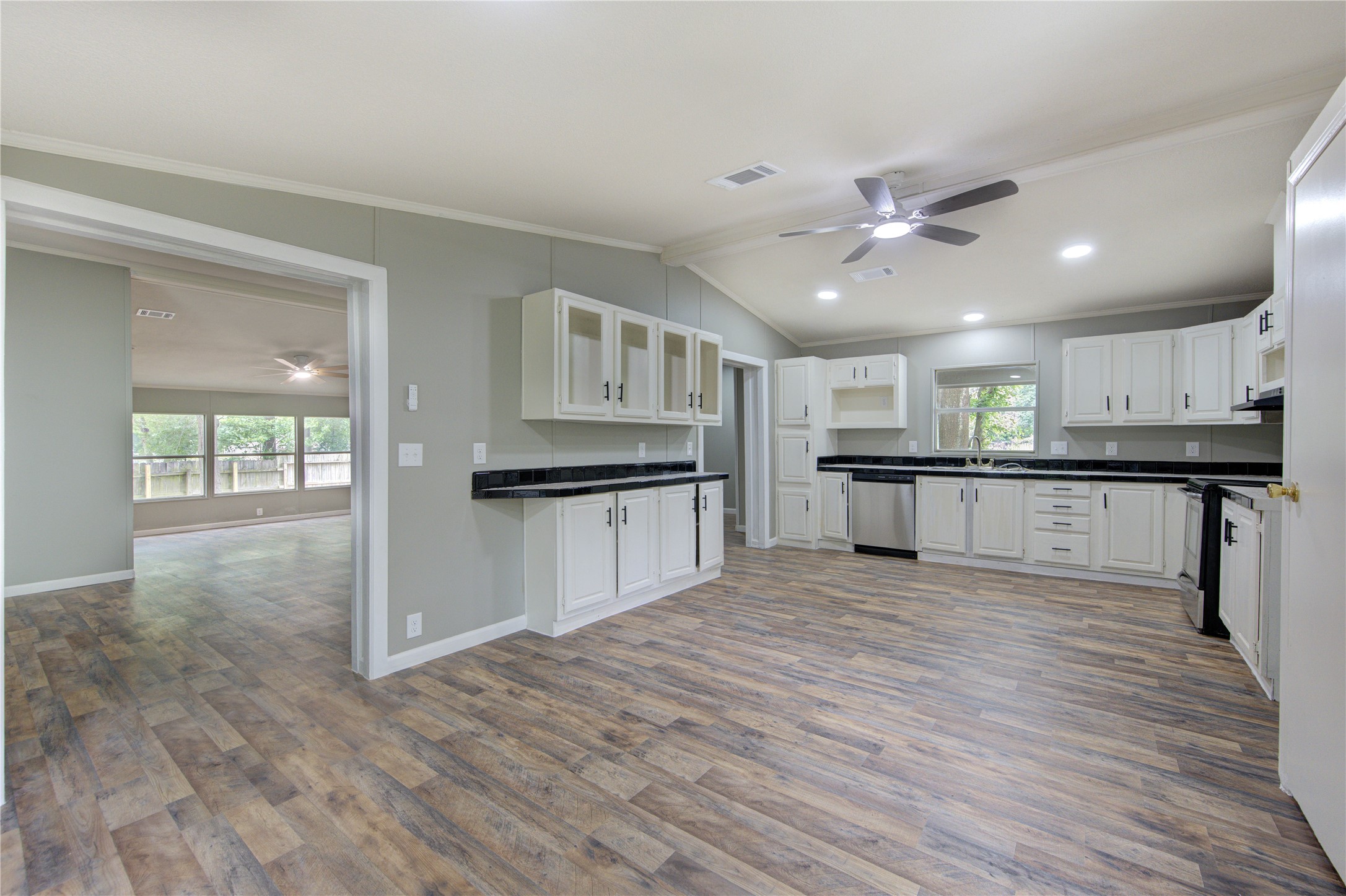 30226 Davis Street Magnolia, TX 77355 - Photo 17 of 50 This spacious, open-concept kitchen features modern appliances, white cabinetry, and sleek countertops. It flows seamlessly into a bright living area with large windows and wood-style flooring, creating a warm, inviting atmosphere.