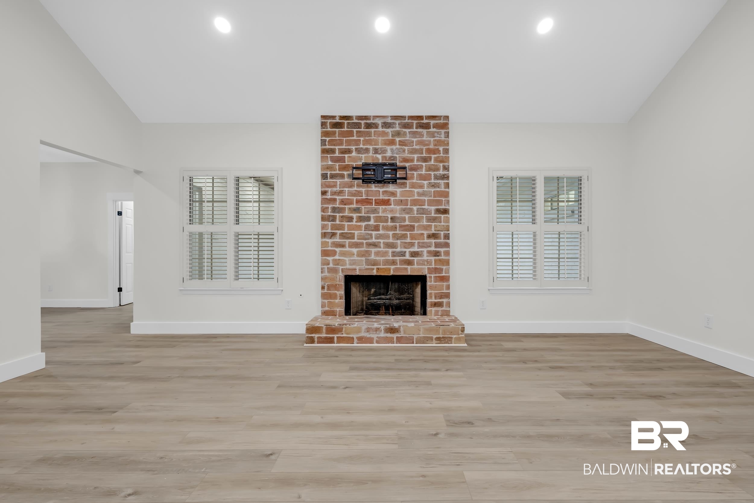 4924 Brooke Court Mobile, AL 36618 - Photo 10 of 34 Unfurnished living room featuring a brick fireplace, vaulted ceiling, light wood-style flooring, and recessed lighting