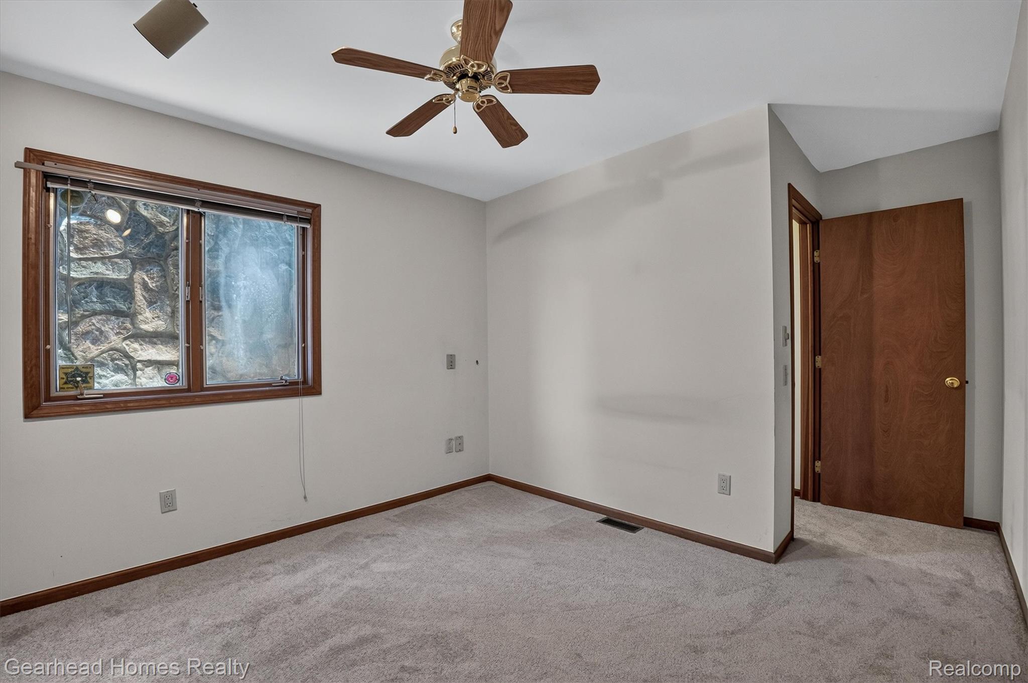 3486 West Drahner Road Oxford, MI 48371 - Photo 15 of 51 Wood-trimmed window with stone wall exterior, light gray wall paint, and gray carpeting