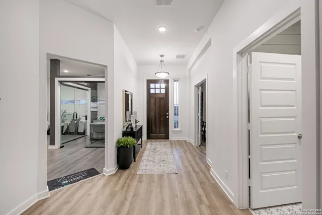 a view of a hallway with wooden floor and a bathroom