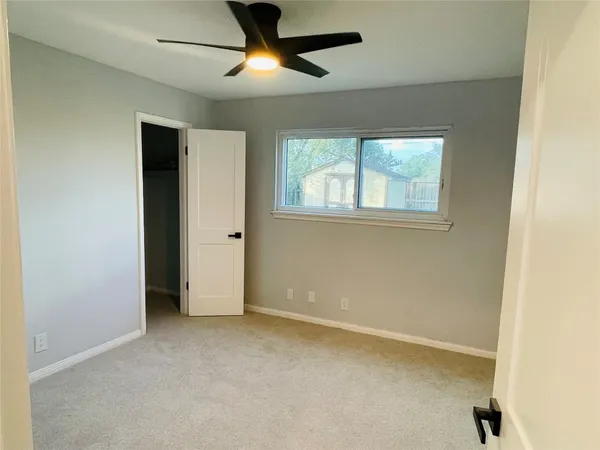 an empty room with windows and fan