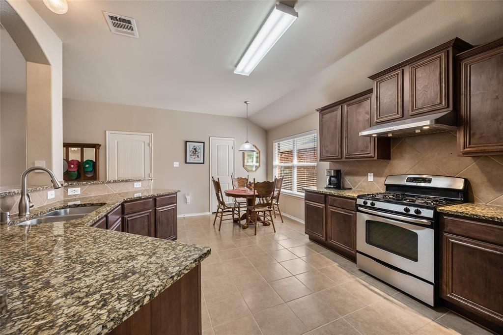 1260 Highbluff Lane Rockwall, TX 75087 - Photo 8 of 22 a kitchen with stainless steel appliances granite countertop a stove top oven a sink a dining table and chairs