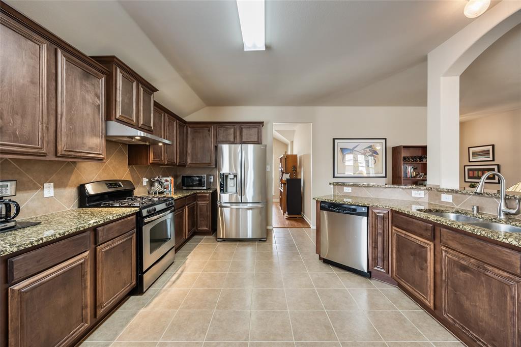 1260 Highbluff Lane Rockwall, TX 75087 - Photo 10 of 22 a large kitchen with stainless steel appliances granite countertop a stove top oven a sink dishwasher a refrigerator and cabinets with wooden floor