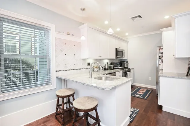 a kitchen with a sink a stove a refrigerator and a dining table with wooden floor