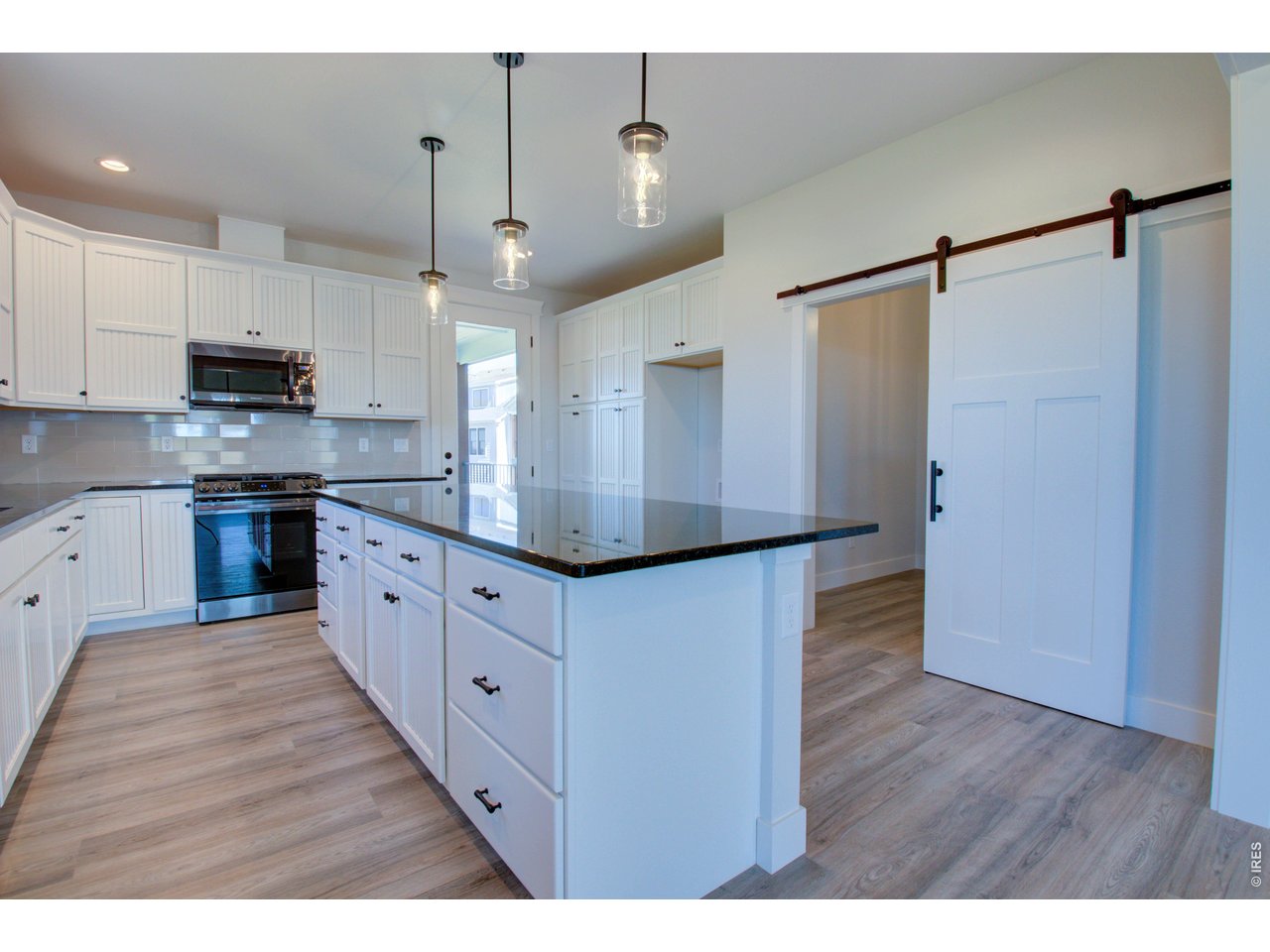 5705 2nd Road Greeley, CO 80634 - Photo 15 of 46 Custom Alpine bead board cabinetry with 42" uppers and soft-close doors & drawers. The barn door opens to the adjacent pocket office/flex space