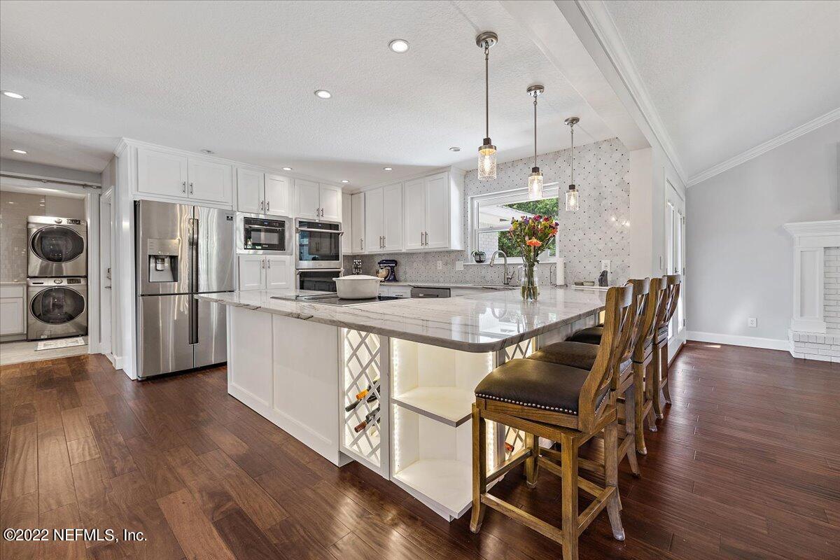 9410 Woodhaven Road Jacksonville, FL 32257 - Photo 7 of 27 a kitchen with stainless steel appliances granite countertop a table chairs wooden floors and a view of living room
