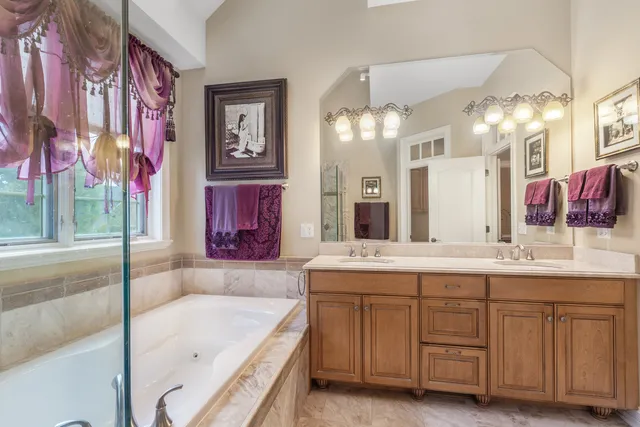 a bathroom with a bathtub a double vanity sink and a large mirror