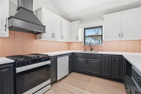 a kitchen with granite countertop stainless steel appliances a sink dishwasher a stove and white cabinets