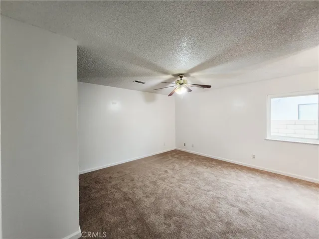 an empty room with a window and a ceiling fan