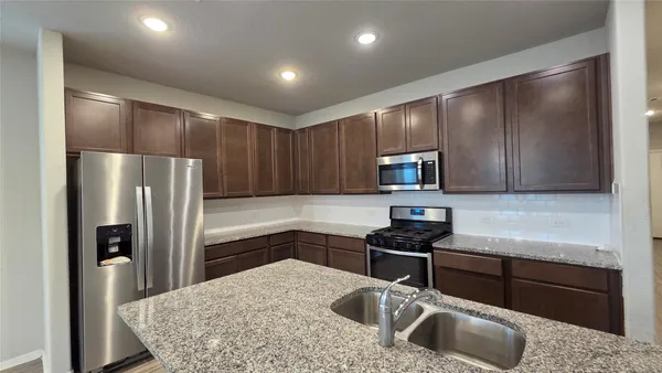 a kitchen with kitchen island granite countertop a sink stainless steel appliances and cabinets